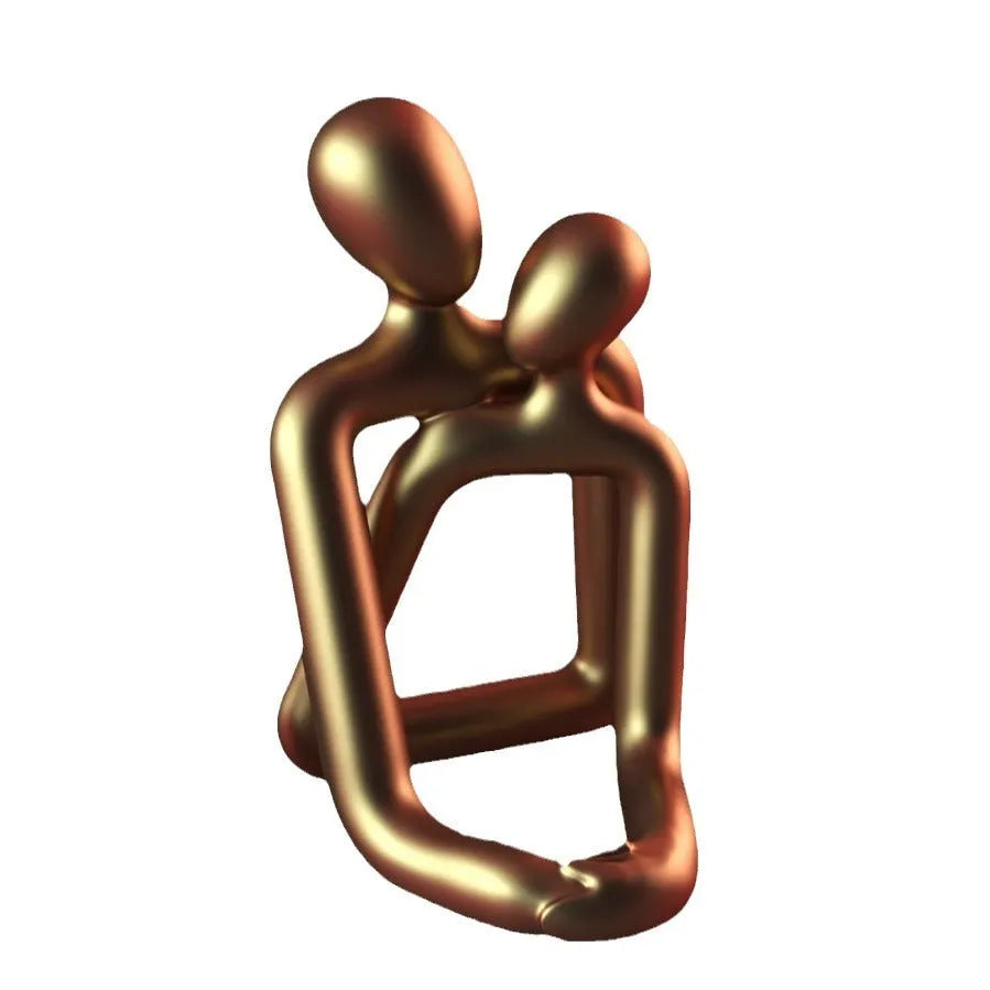 Modern resin statue of a loving couple in gold or milky white colour on a wooden surface.