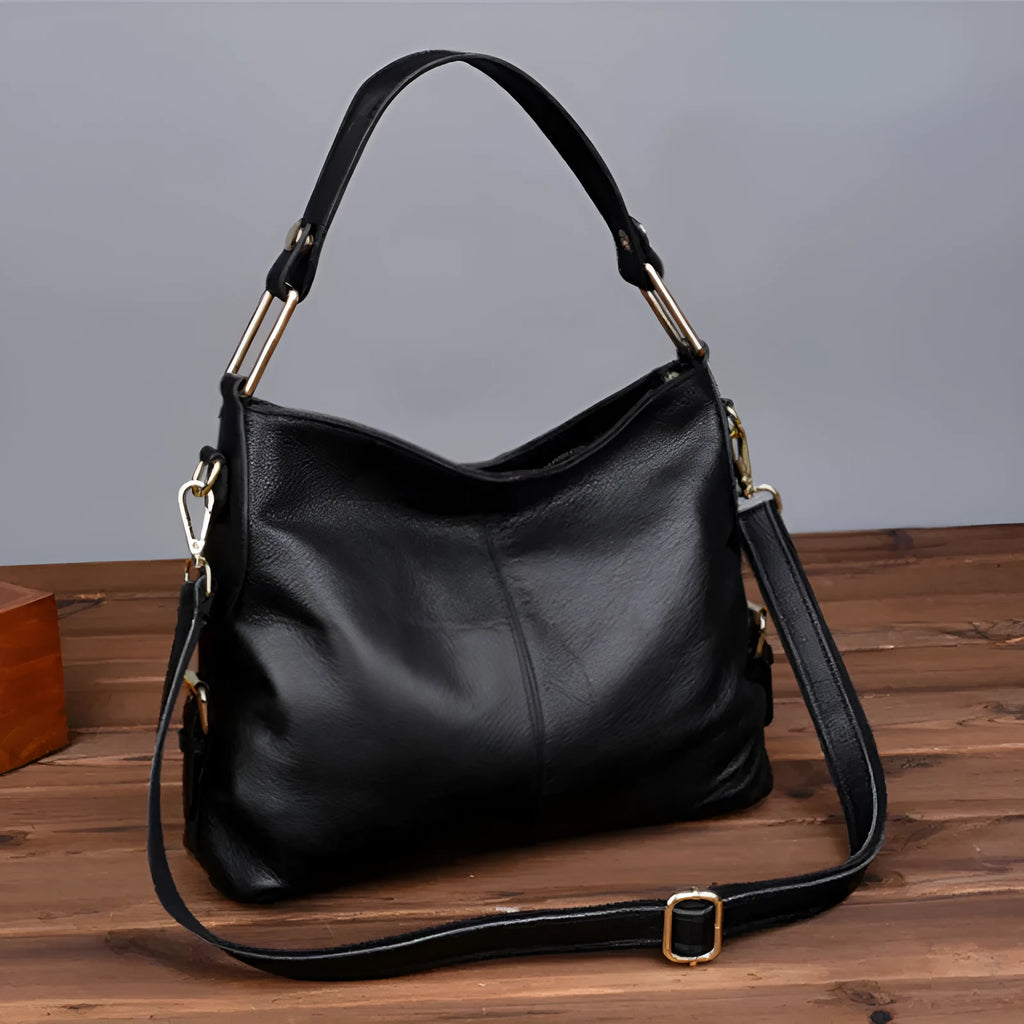 Genuine leather vertical square crossbody bag in black with sewing line detail and external pocket.