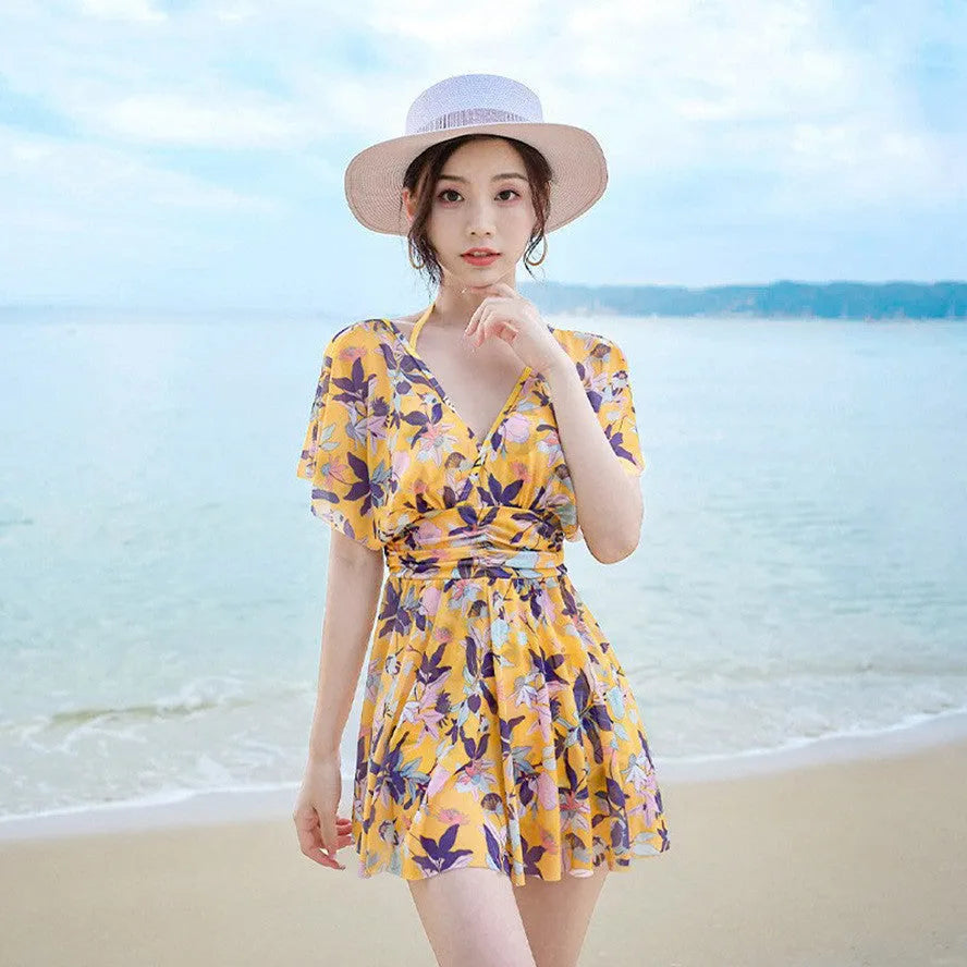 Yellow floral print women's one-piece swimsuit with skirted design on mannequin.