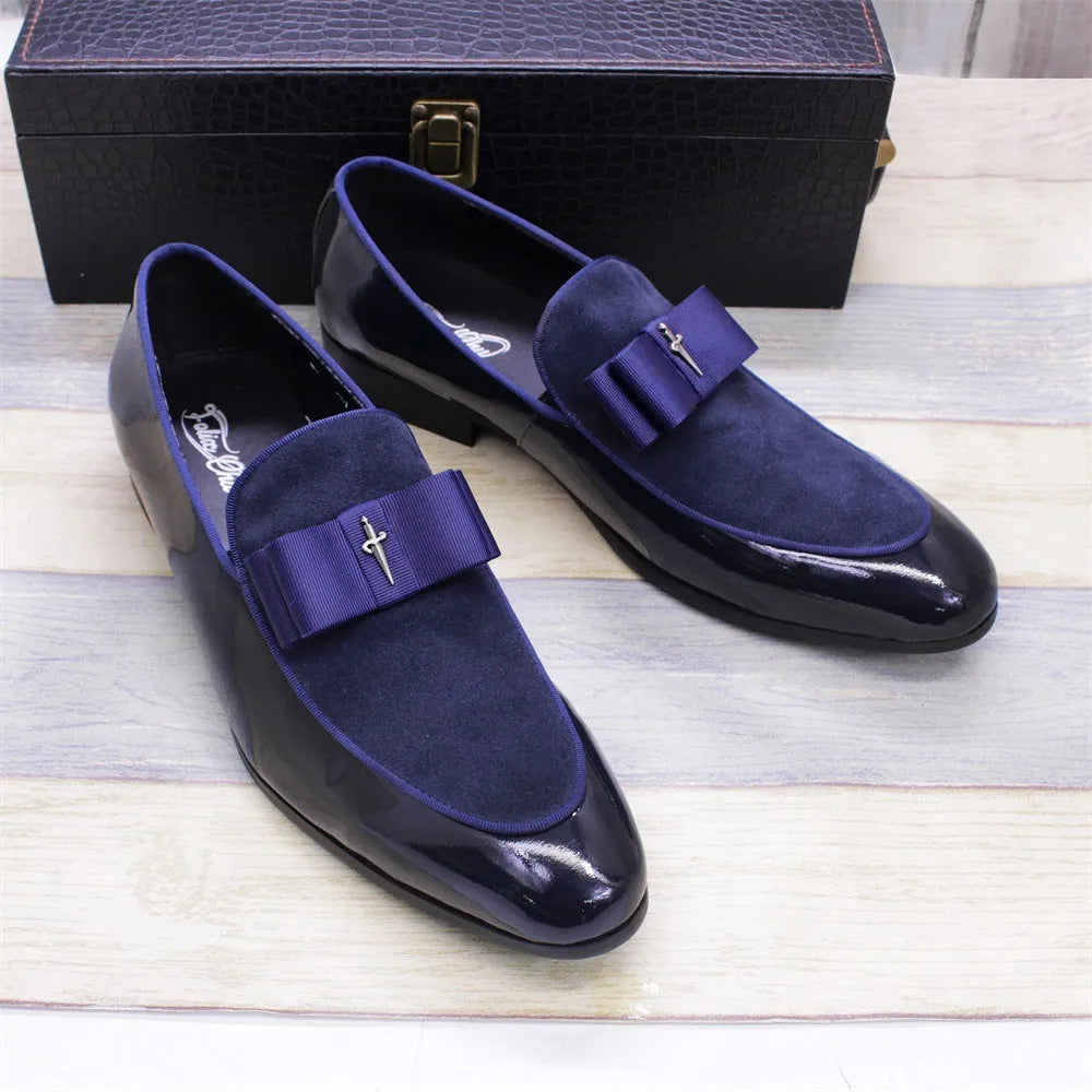 Men's black patent leather tassel loafers with a matte toe, shown on a wooden floor.