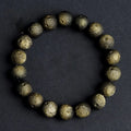 Close-up of an obsidian crater ball bead bracelet in a gold meteorite finish, showing its textured spherical beads.