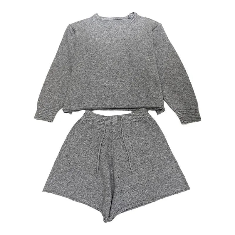 Woman wearing a loose beige knitted long-sleeve sweater and wide-leg shorts set, casual two-piece outfit.