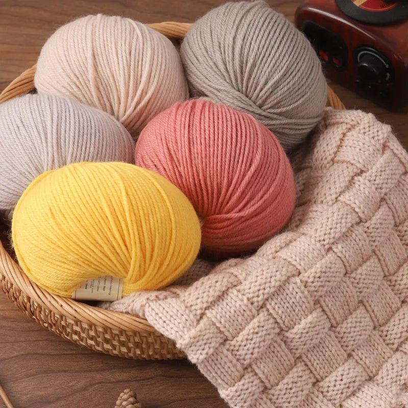 One roll of beige domestic wool hand-knitting yarn for size 10 needles next to knitting needles.