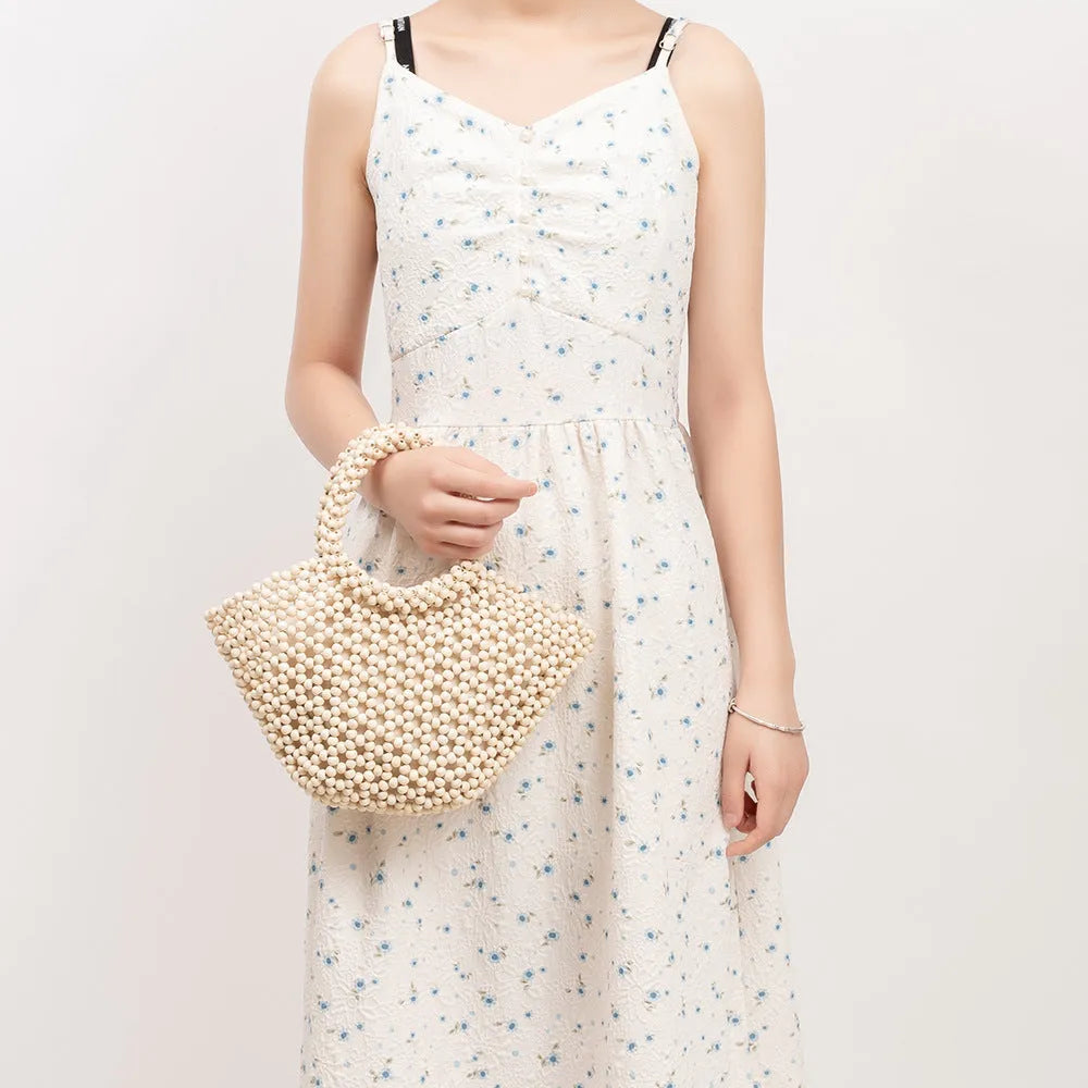 Hand-woven wooden bead beach bag in dumpling shape with strapless design.