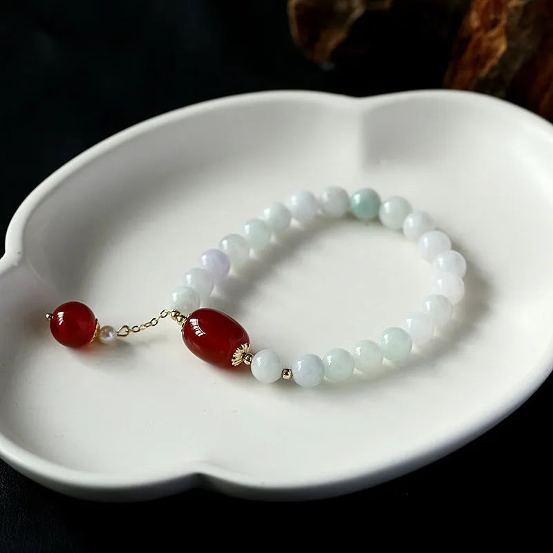 Women's ethnic bracelet with hanging red agate tassel on a gold chain.