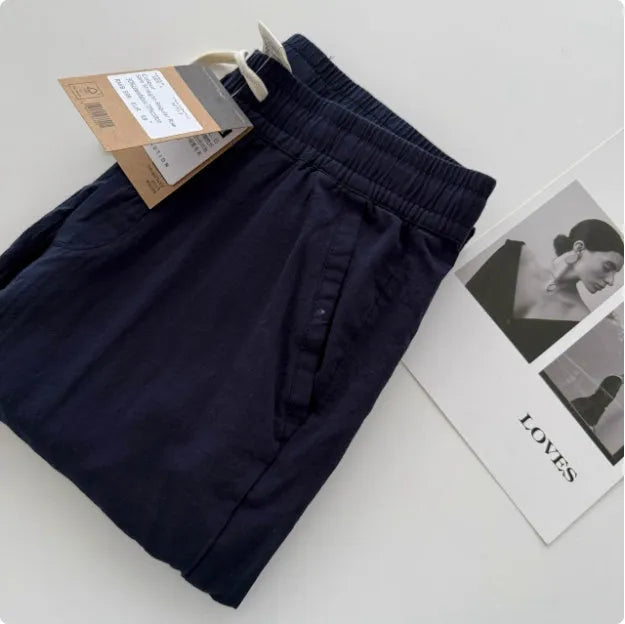Men's beige loose straight leg casual trousers with an elasticated drawstring waistband laid flat.