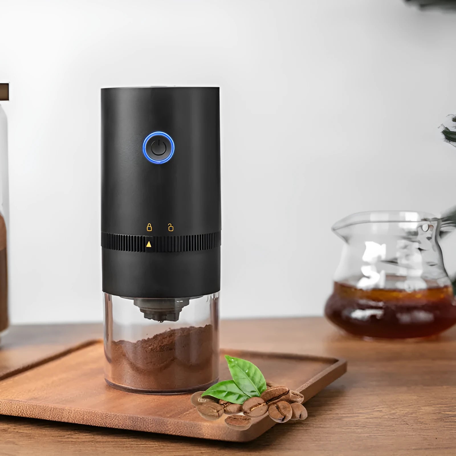 Black and white portable USB-C electric coffee grinder with transparent chamber on a kitchen counter