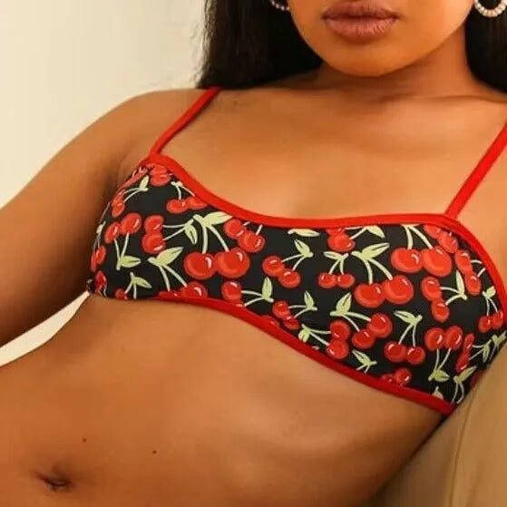 Women's cherry and floral print bikini swimsuit set with tube top and briefs on a neutral background.