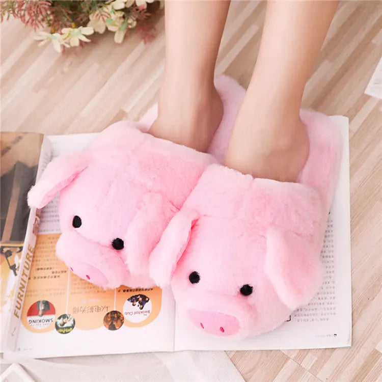 Pink pig-shaped plush house slippers with a short pile exterior, shown on a plain background.