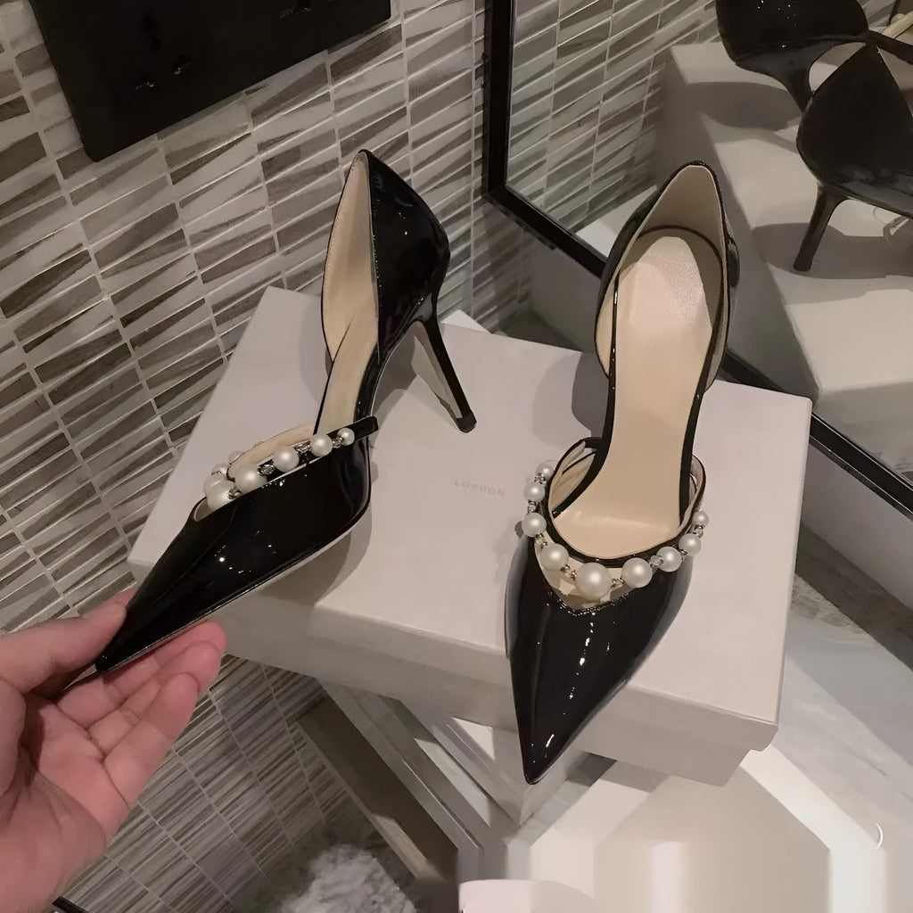 Women's pointed patent leather stiletto high heels with pearl detail on the heel.