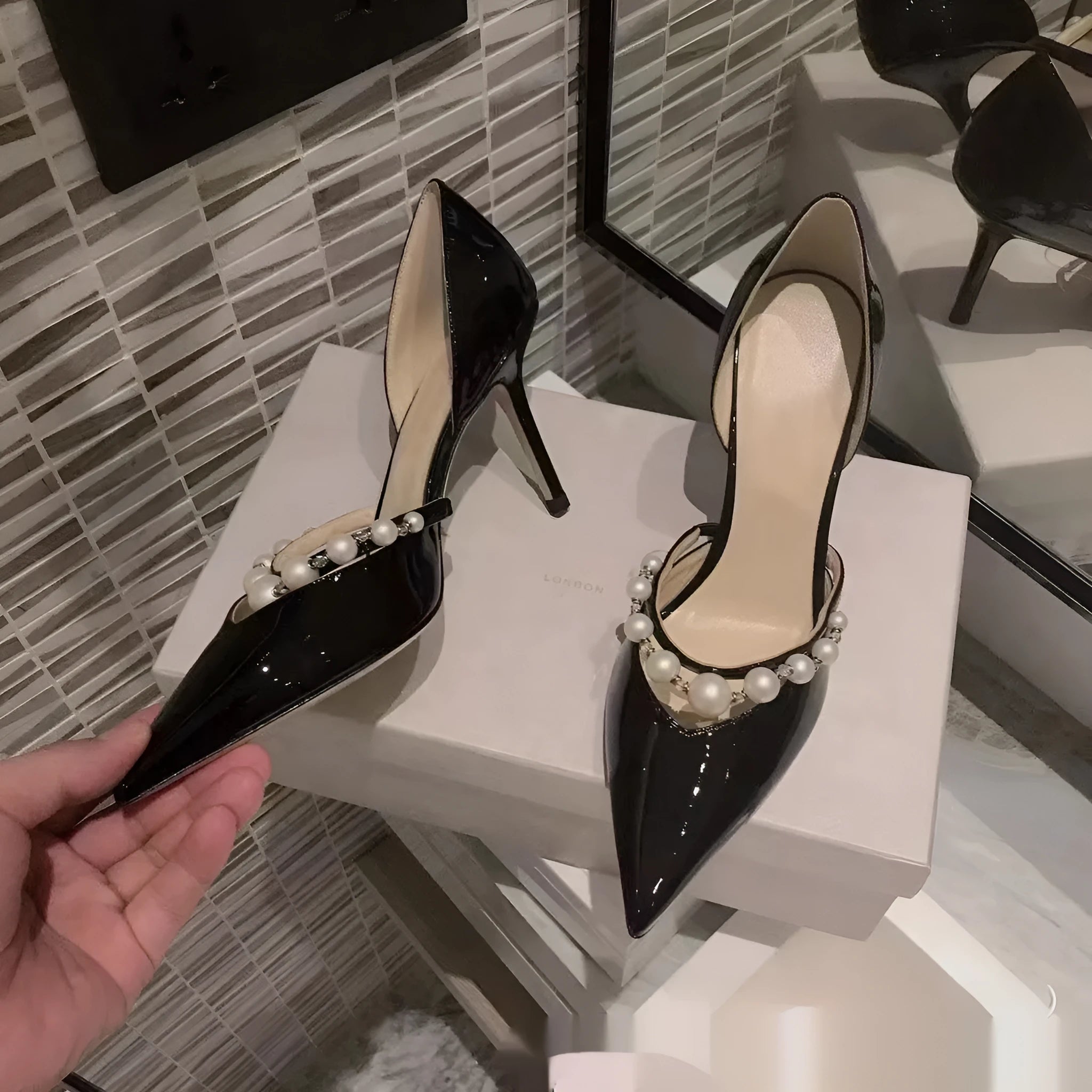 Women's pointed patent leather stiletto high heels with pearl detail on the heel.