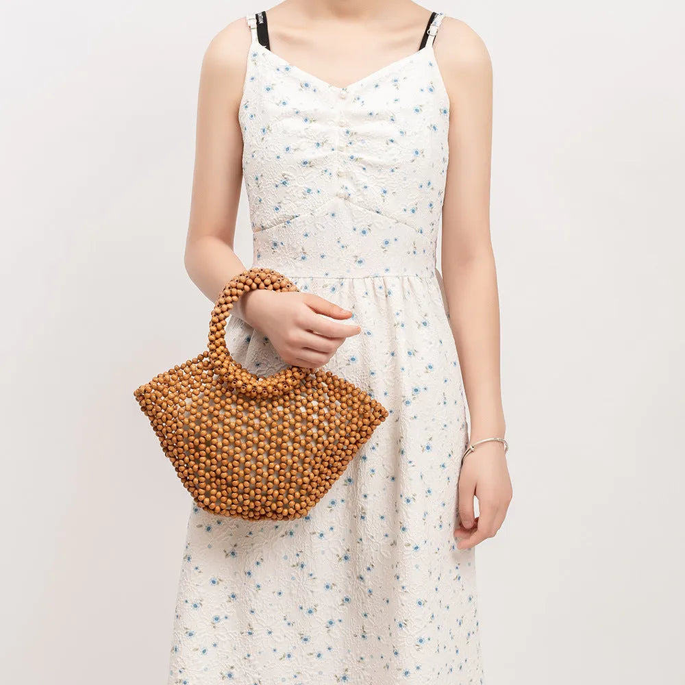 Hand-woven wooden bead beach bag in dumpling shape with strapless design.