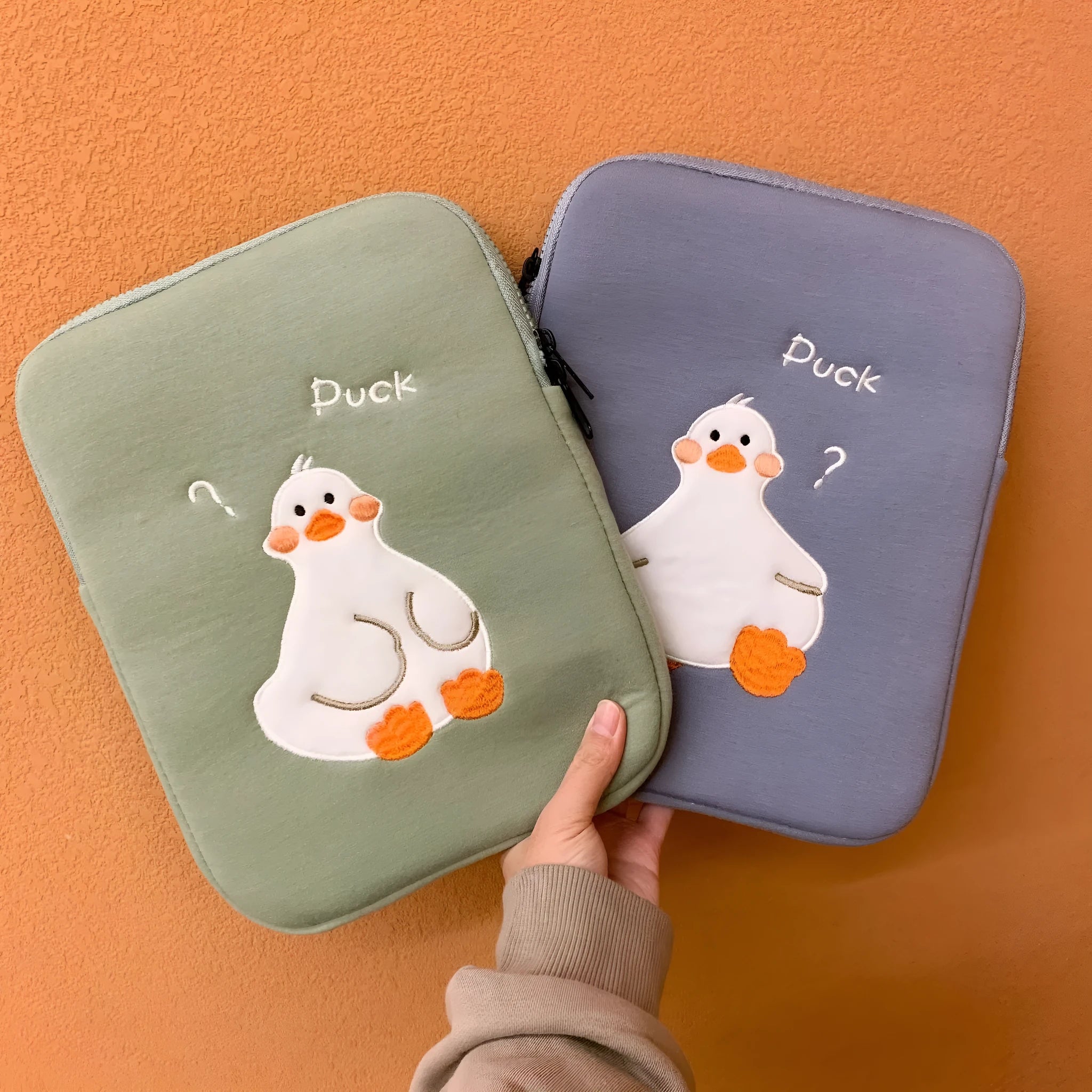Blue cotton tablet case with embroidered cartoon duck design and a silver zipper.