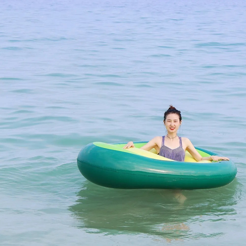 Green inflatable giant avocado pool float on water, showing its large 169x130cm size and smooth surface.