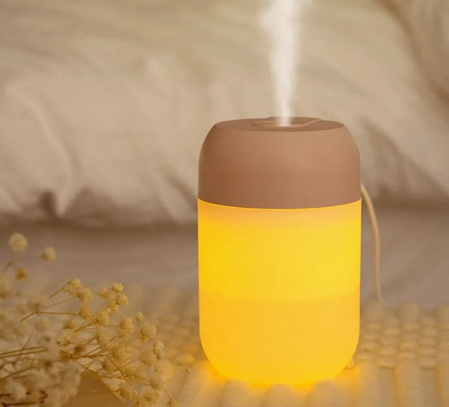 White cylindrical mini humidifier with USB cable on a wooden surface.
