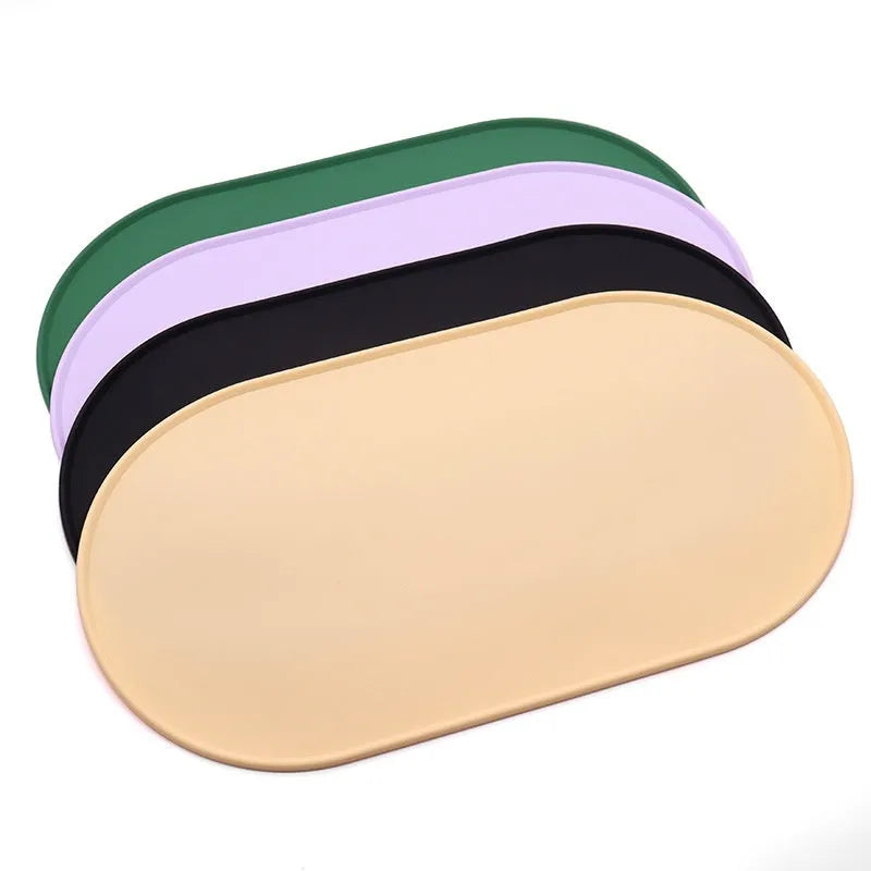 Green silicone cat feeding mat with raised edge holding a food bowl and water bowl on a kitchen floor.
