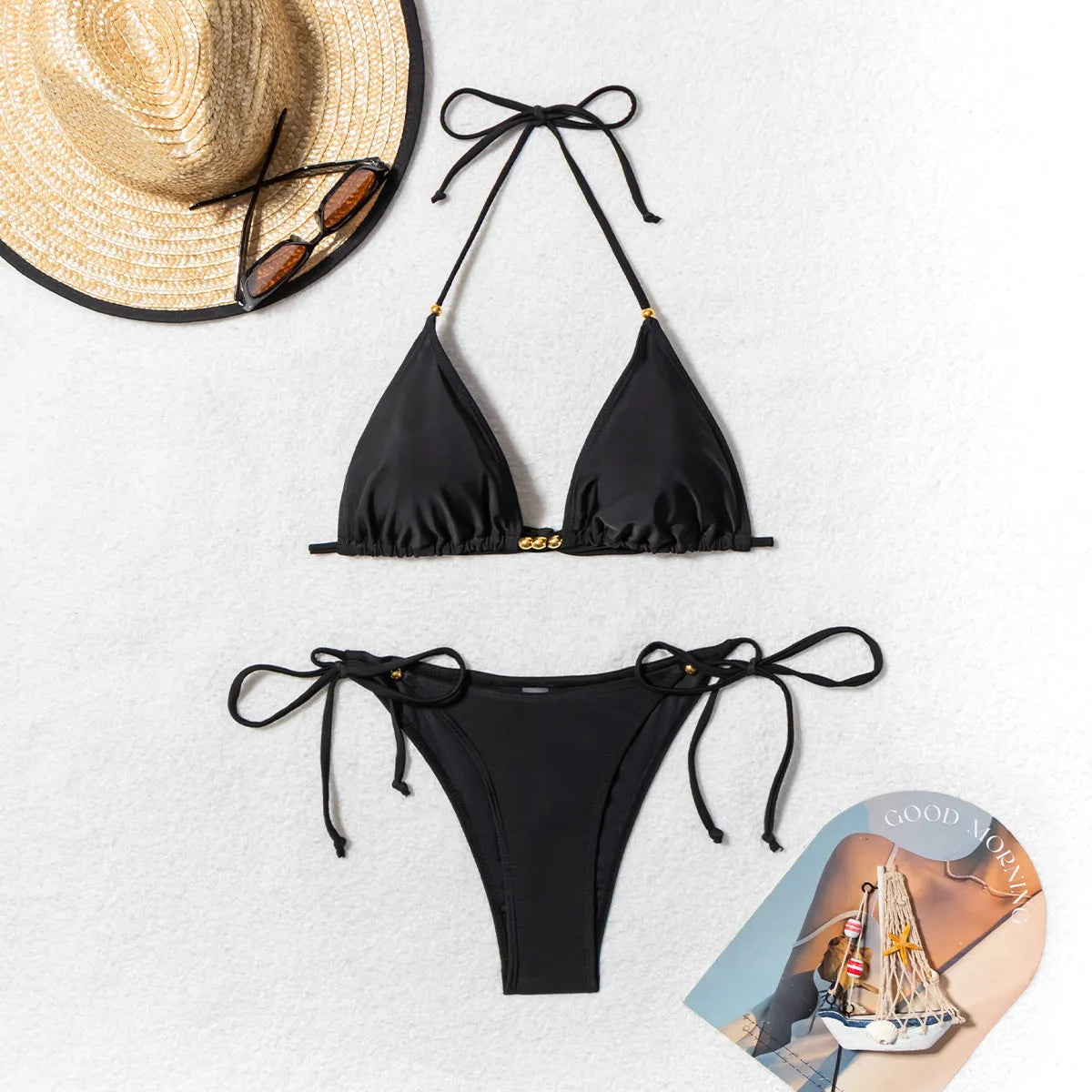 Black women's bikini swimsuit with metal bead details and a split design.