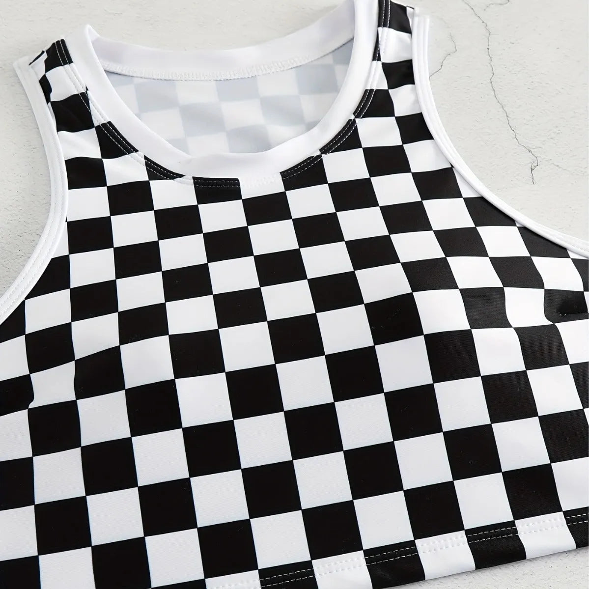 Women's black and white checkerboard plaid backless racing swimsuit with suspender straps.