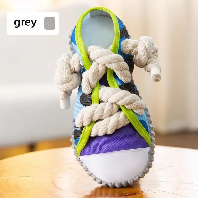 Grey and white dog toy slipper with black laces, blue sole, and a bell on the side