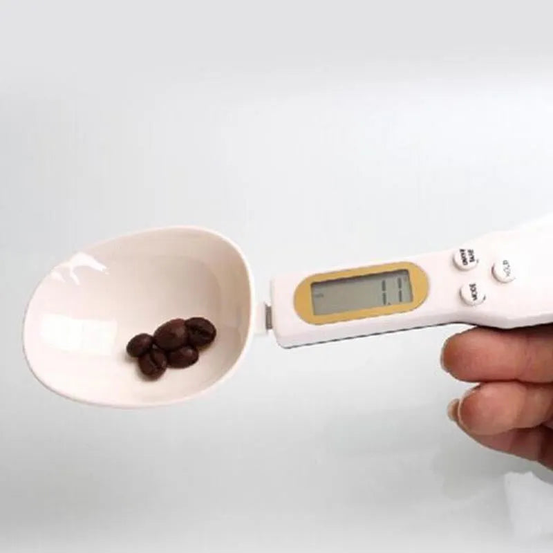 White digital spoon kitchen scale with LCD screen showing weight measurement.