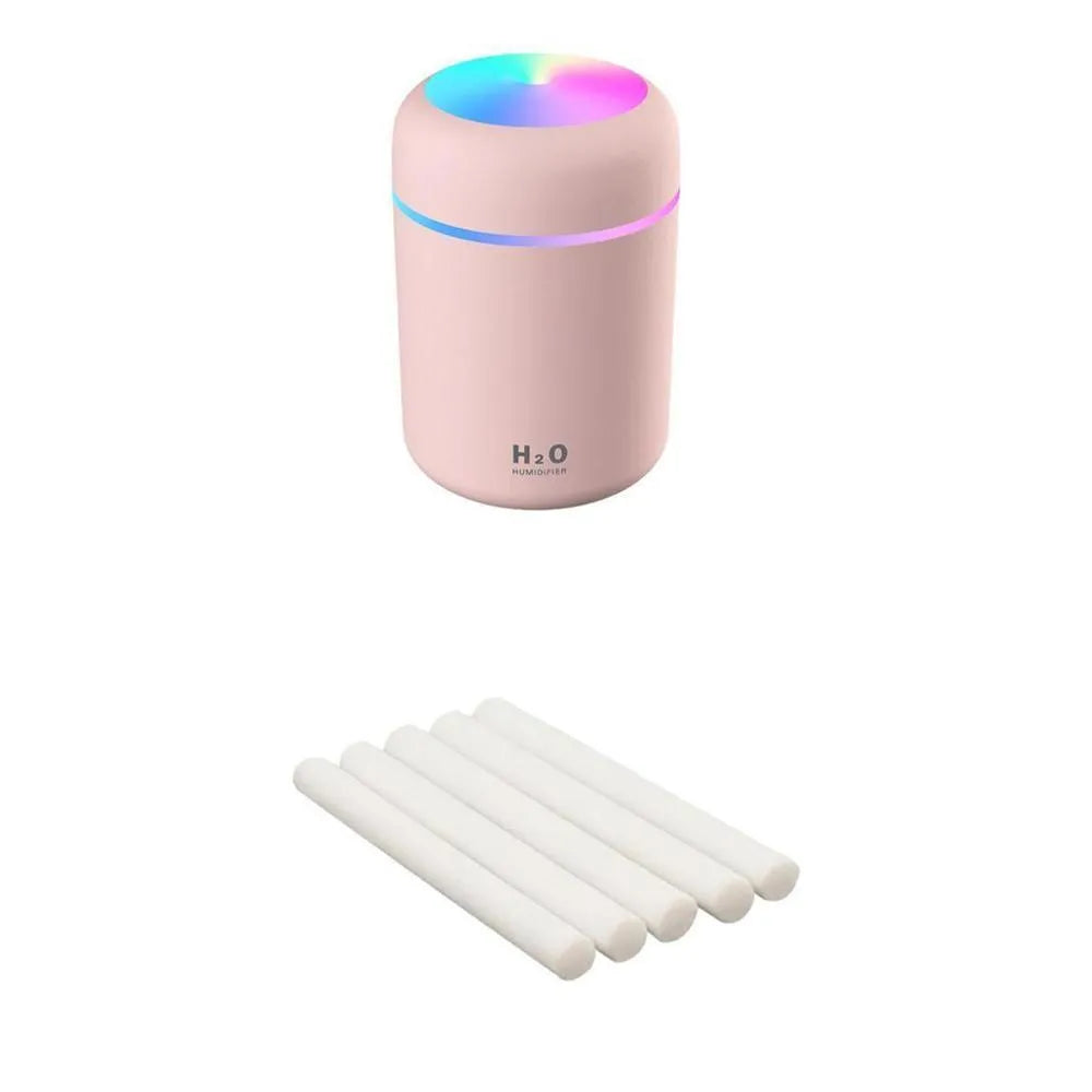 Pink USB desktop humidifier with colourful lights and water tank on wooden surface