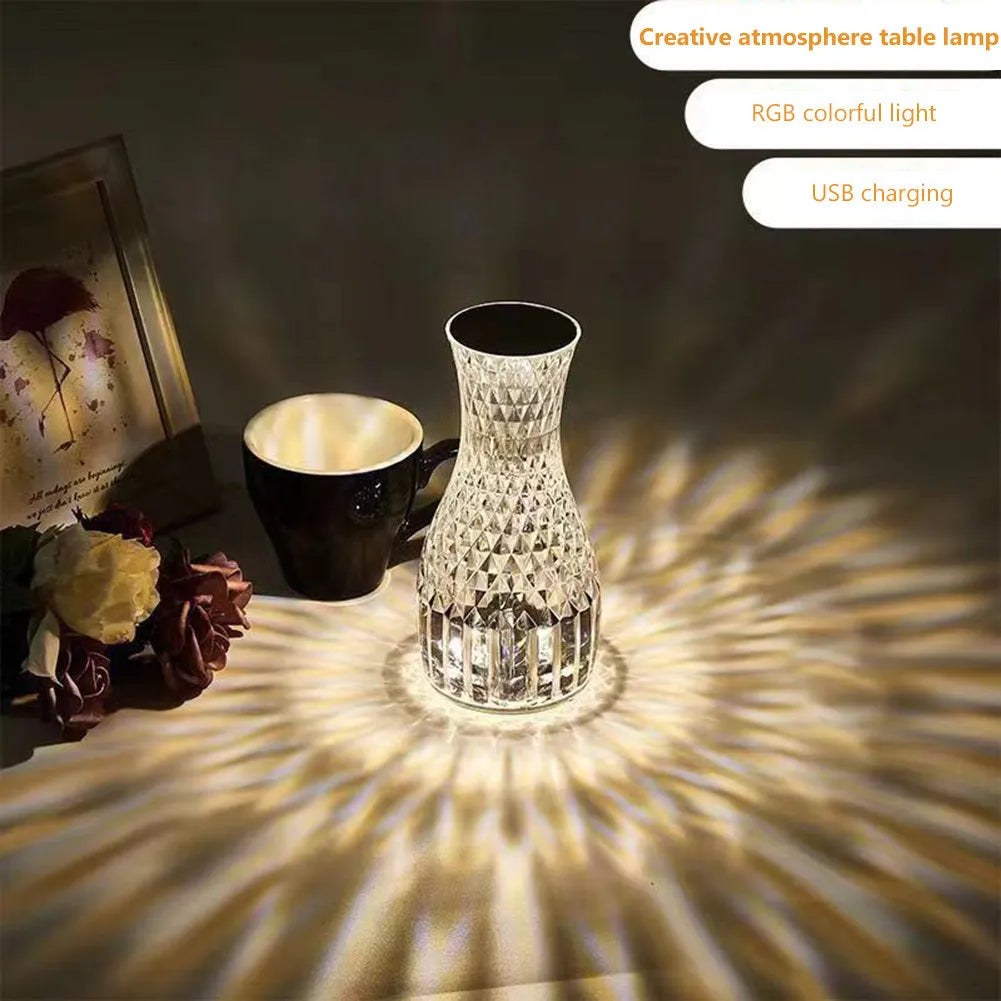 Vase-shaped transparent crystal bedside lamp with touch controls and LED lights on a table.