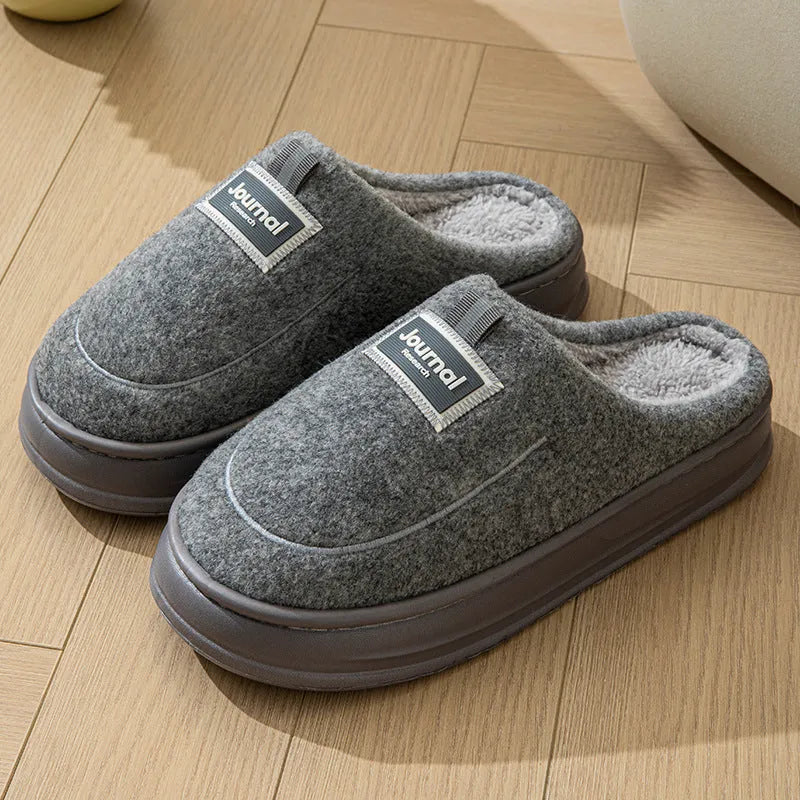 Men's brown suede slippers with a thick, textured sole on a wooden floor
