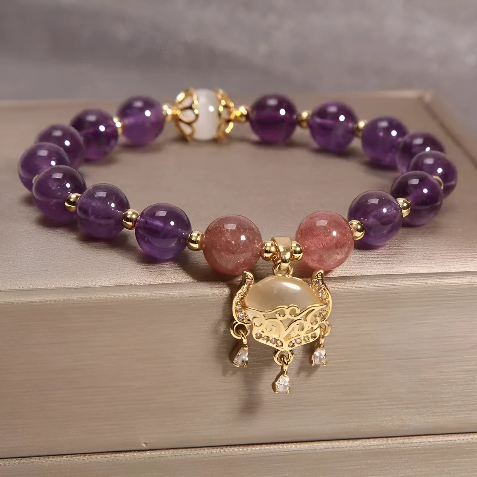 Women's copper bracelet with natural amethyst stones, gold accents, and a longevity lock charm