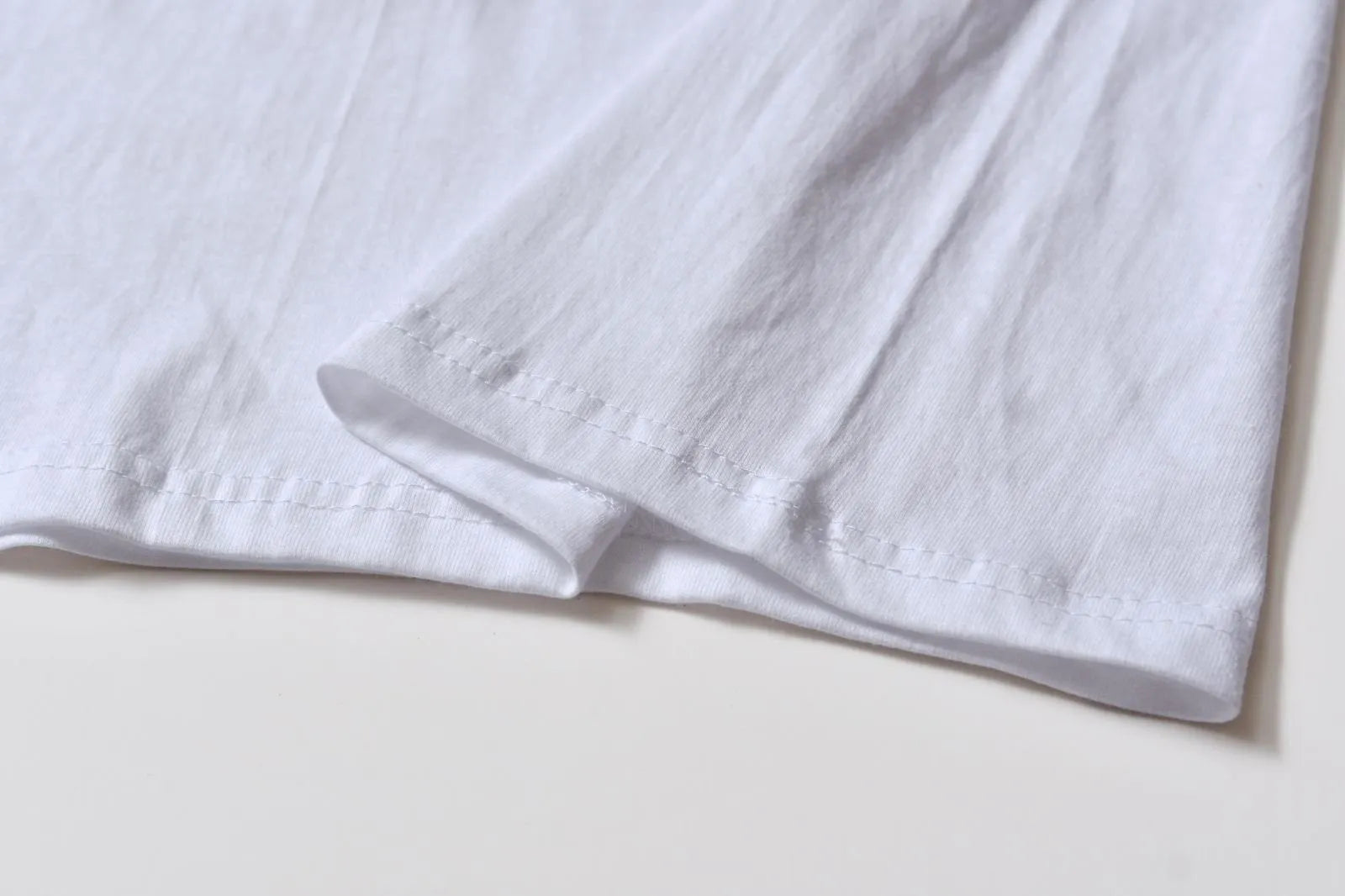 White cotton T-shirt overalls with a round neck and short sleeves, shown in a loose pullover style.