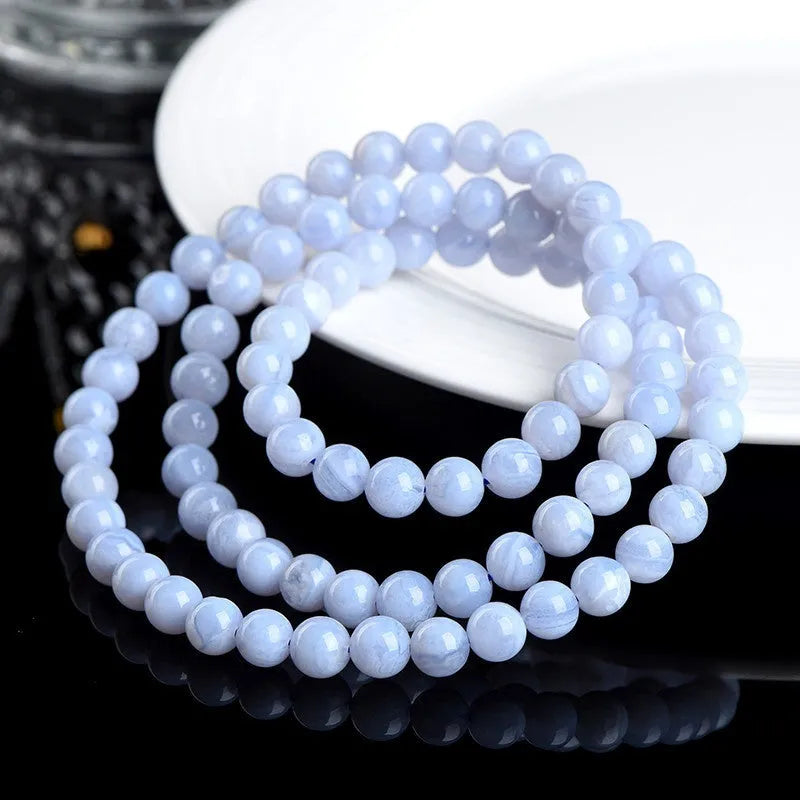 Blue agate bracelet with striped beads and a Ruyi charm on a wrist.