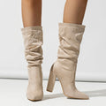 Black suede women's boots with a chunky high heel and pointed toe, shown on a middle calf.