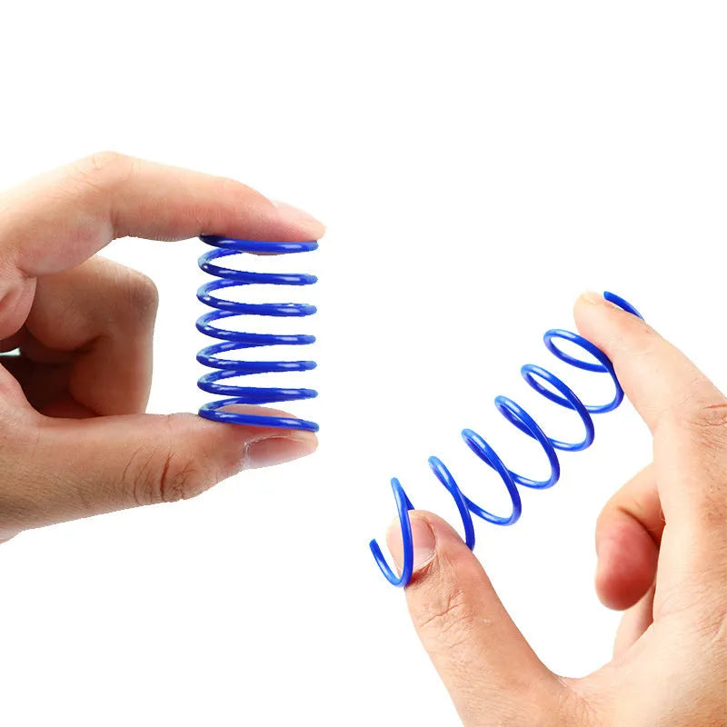 Colourful plastic coil spring toys for cats on a wooden floor.