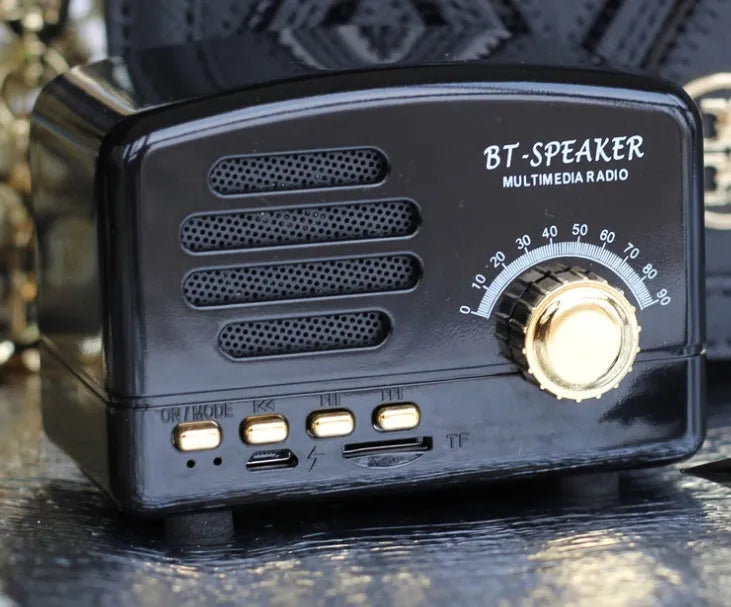 Vintage-style wood grain finish Bluetooth speaker on a table, showing compact size and USB port.