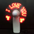 White handheld mini fan with flashing blue and red LED 'I Love You' pattern on a dark background.
