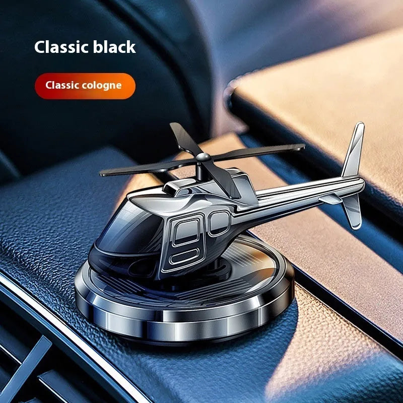 Silver metallic solar-powered helicopter car perfume ornament rotating on a car dashboard