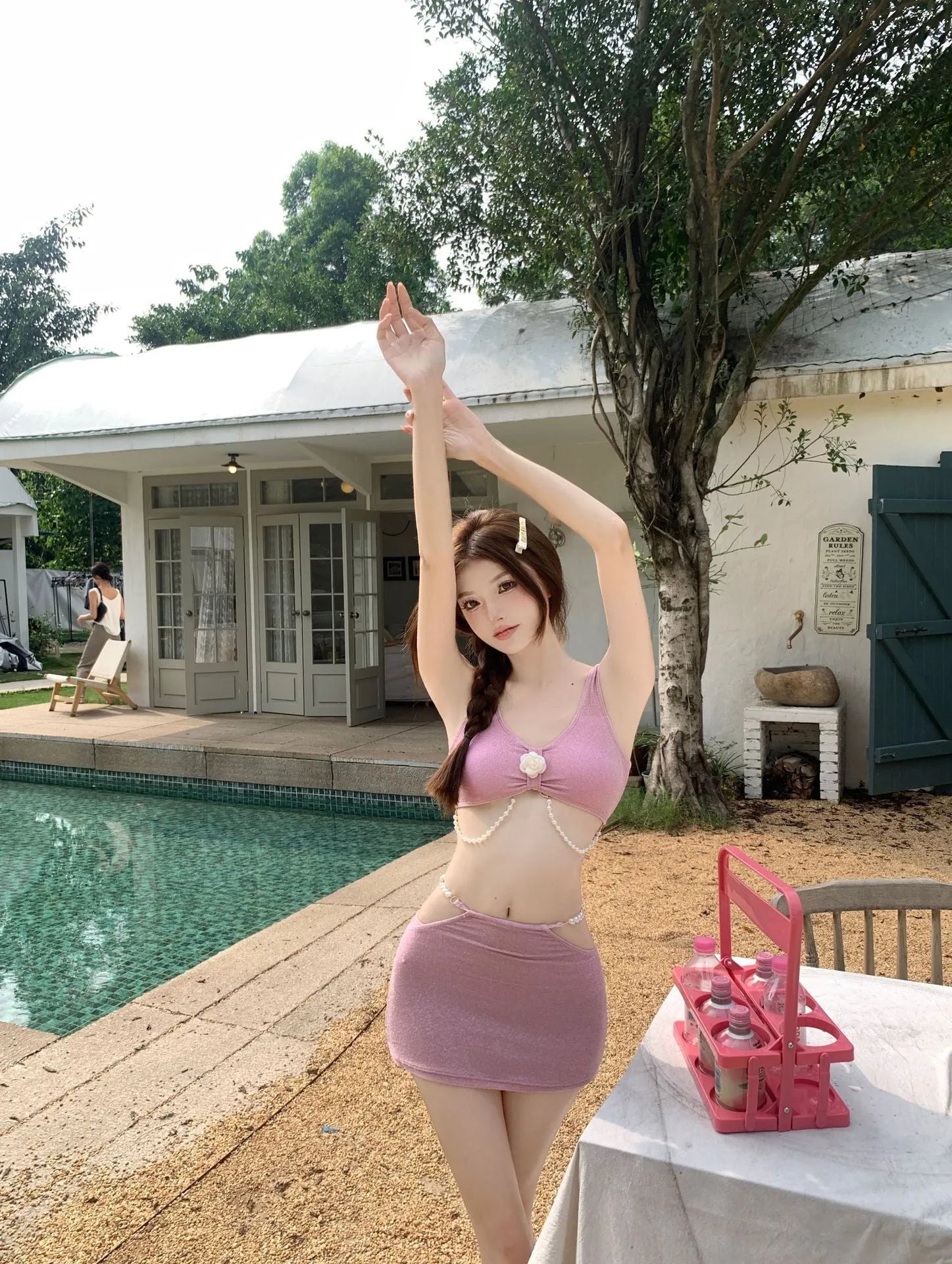 Pink and black three-piece bikini set on a hanger, showing briefs style and sleeveless design.