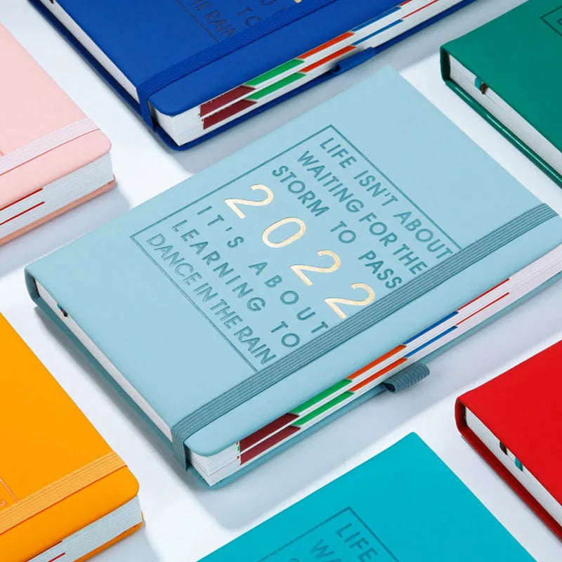 A5 imitation leather notebook with French fold binding open flat on a desk, seven colour options