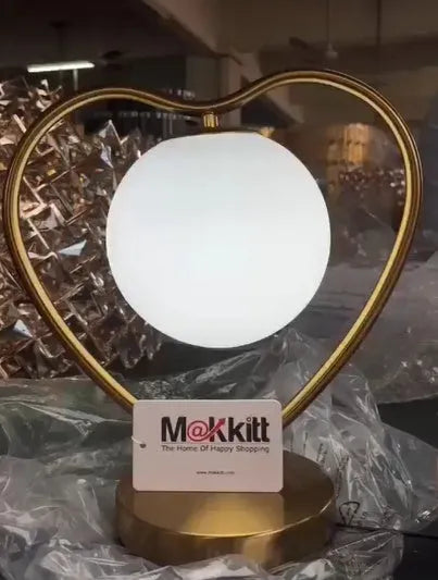 Tall white heart shaped LED table lamp on a wooden surface.
