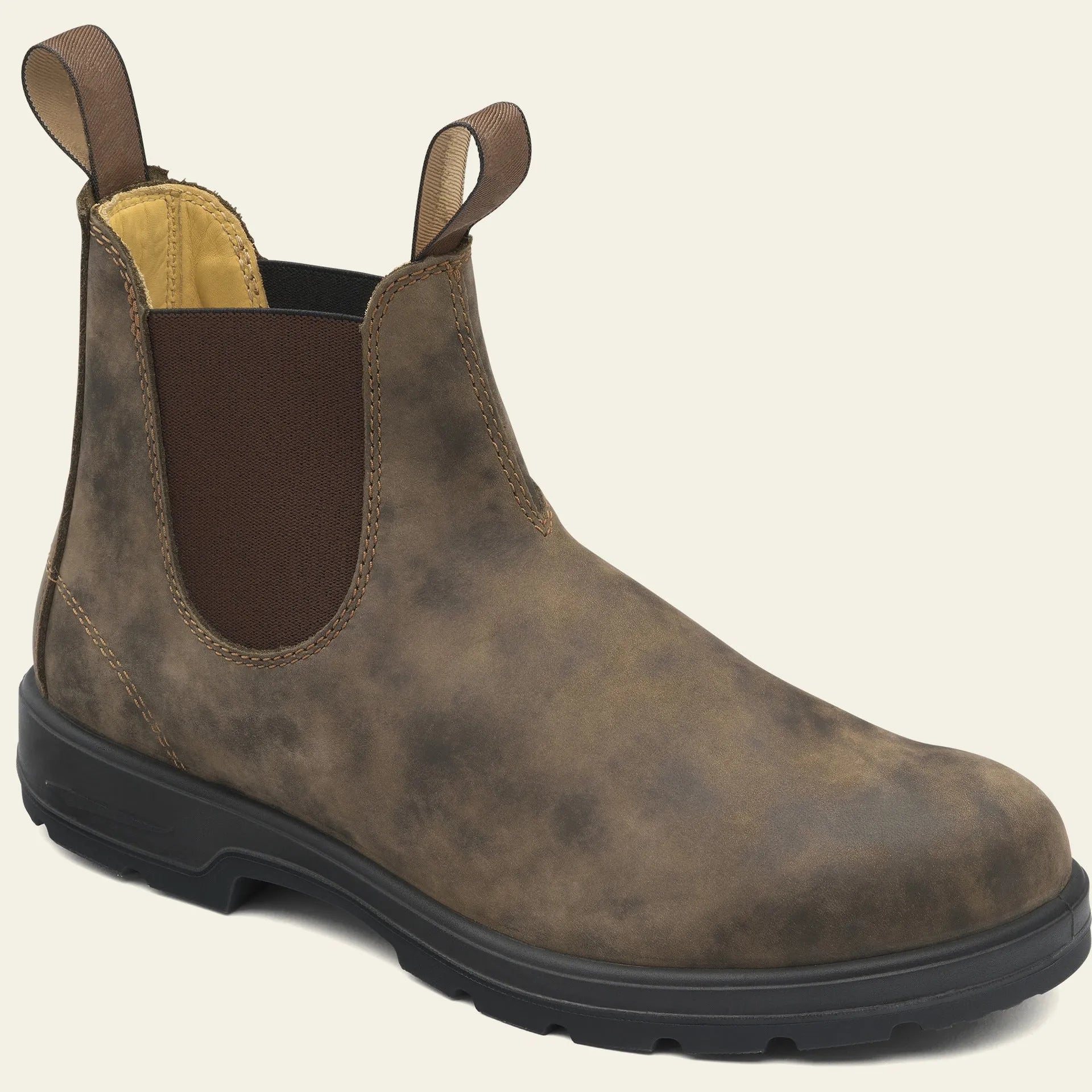 A pair of vintage-style brown Chelsea boots with a round toe and low heel on a wooden floor.