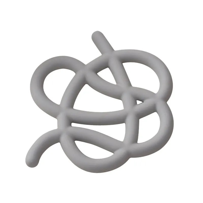Irregular-shaped ceramic heat proof mat in grey with a curved hook for hanging, sitting on a wooden table.