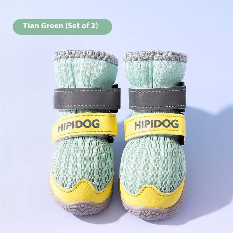 Pair of light blue breathable dog shoes with a cartoon style on a wooden floor.