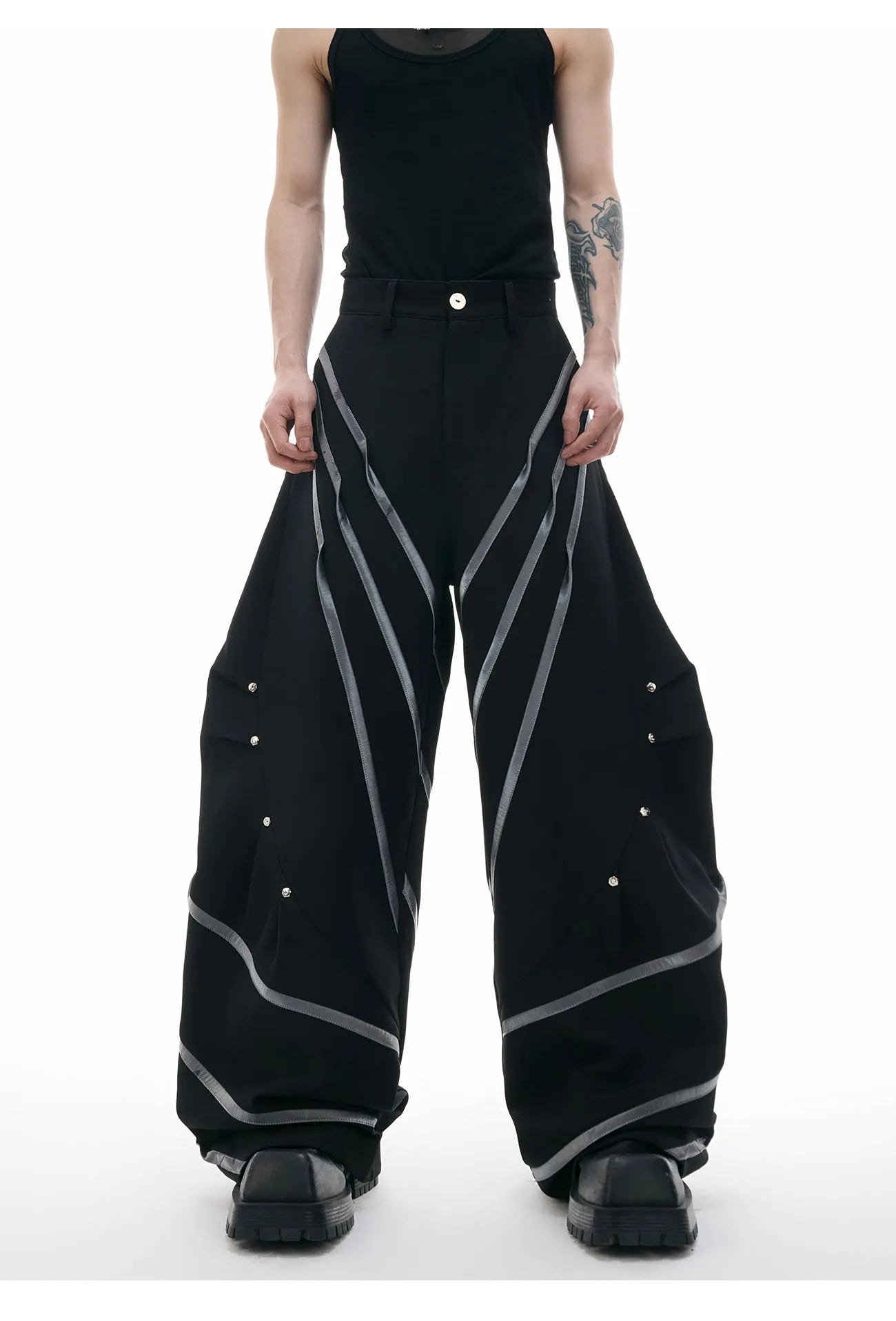 Men's black polyester trousers with metal rivet stripe and front pleats on a white background.