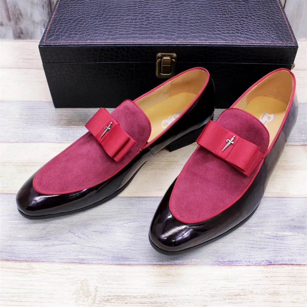 Men's black patent leather tassel loafers with a matte toe, shown on a wooden floor.