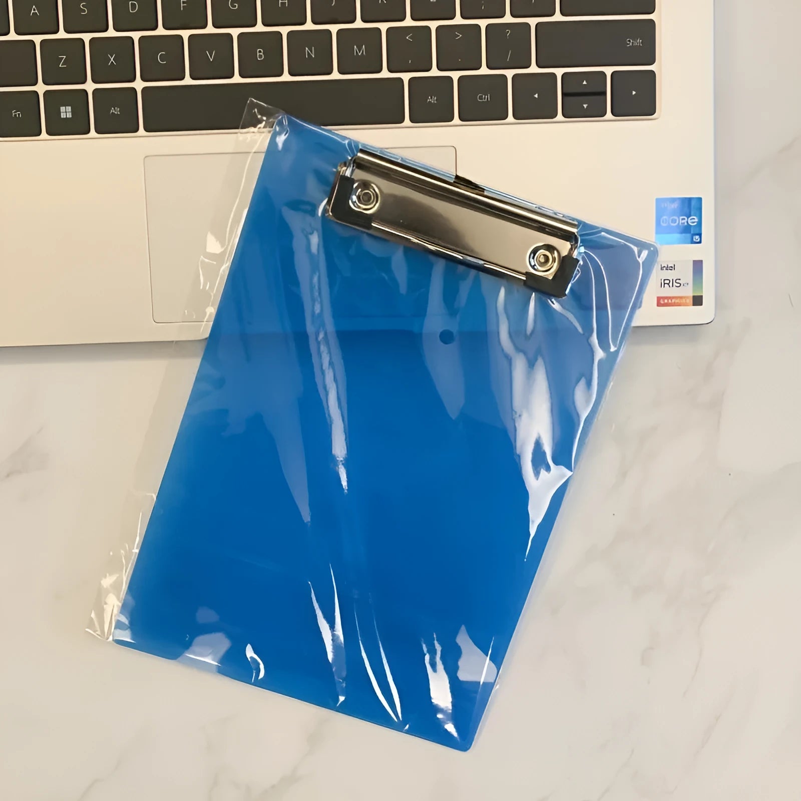 Transparent A4 writing board pad with metal clip holding paper, shown in blue colour option