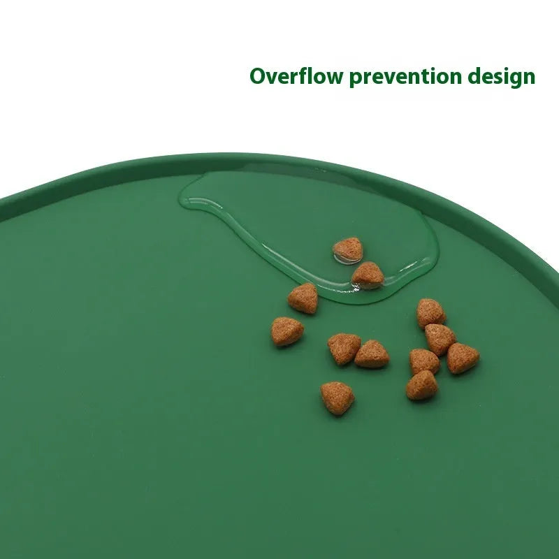 Green silicone cat feeding mat with raised edge holding a food bowl and water bowl on a kitchen floor.