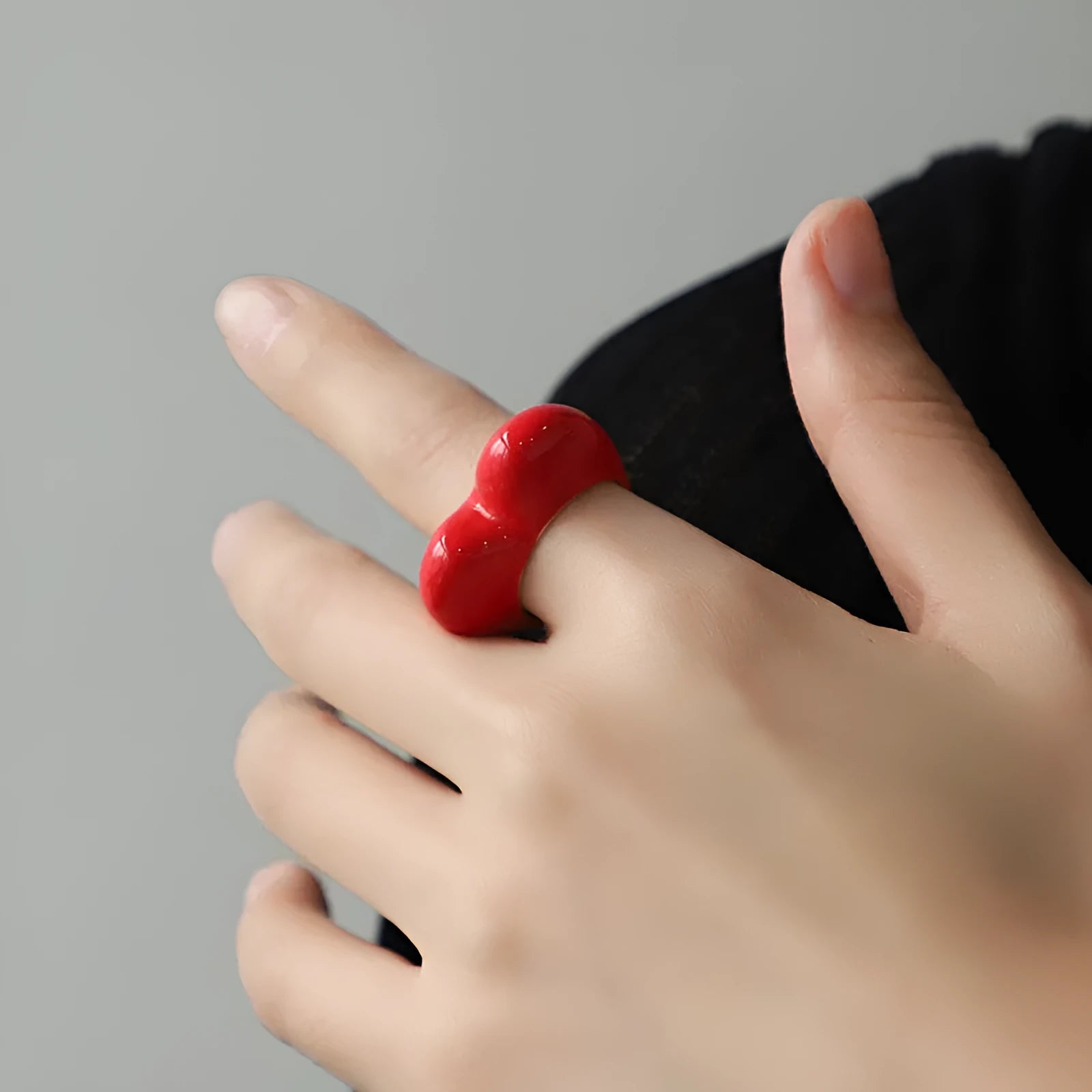 Colourful three-dimensional heart-shaped enamel ring in zinc alloy on a hand.