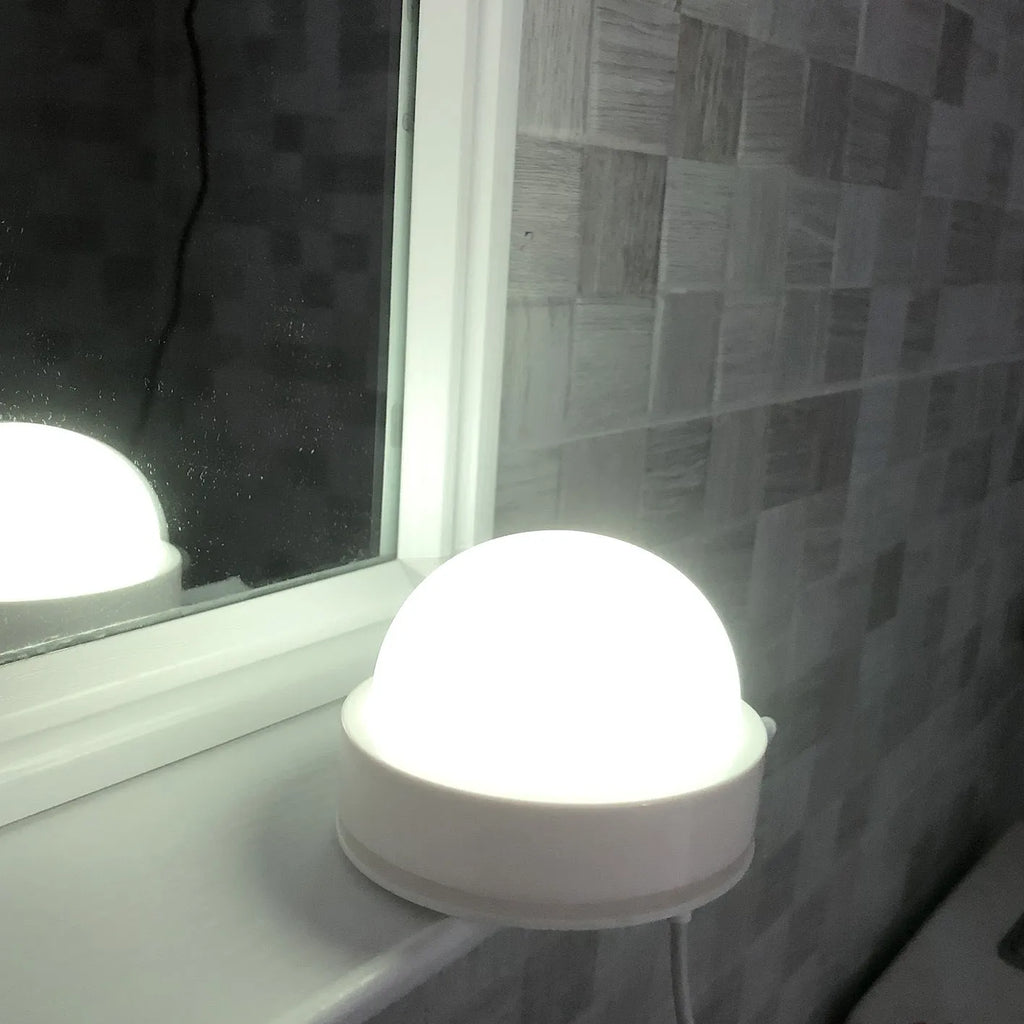 Compact colourful gradient 3D shooting night light with remote control on a desk.