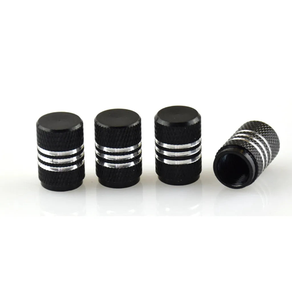 Set of coloured aluminium alloy tyre valve caps for car wheels on a grey background.