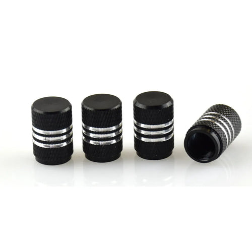 Set of coloured aluminium alloy tyre valve caps for car wheels on a grey background.