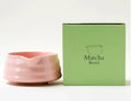 Ceramic matte tea whisk stand in bright white holding a bamboo matcha whisk upright on a wooden tray